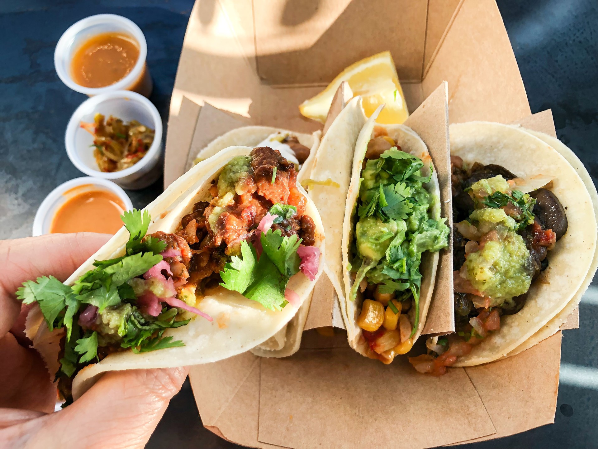 POV of Hand Holding Vegan Taco over Sauces and Pickles