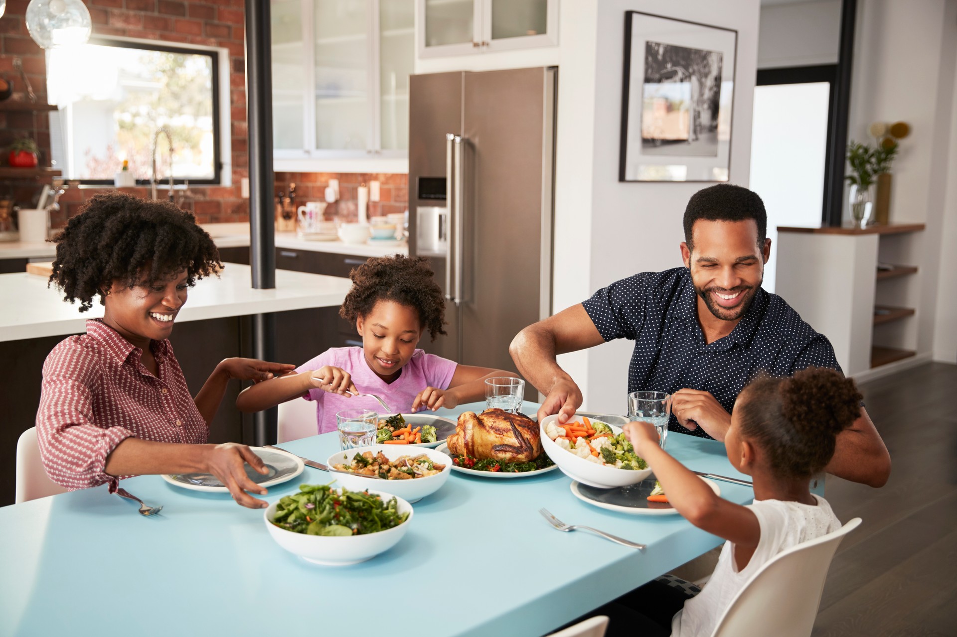 Family Enjoying Meal Around Table At Home Together