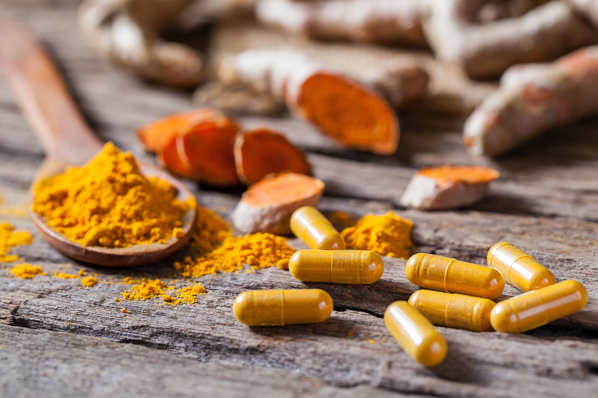 Turmeric powder, turmeric capsule and turmeric on wooden background